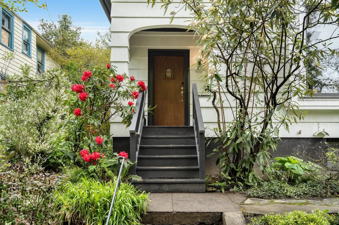 White home entrance with red rhododendrons